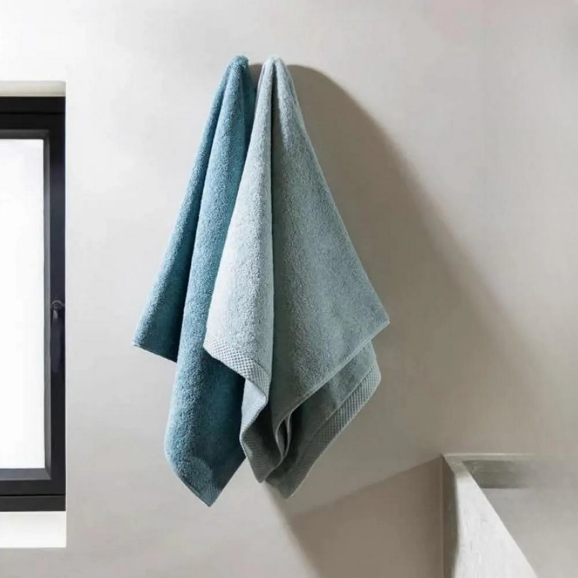 Twee blauwe Florence-handdoeken hangend in een luxe badkamer