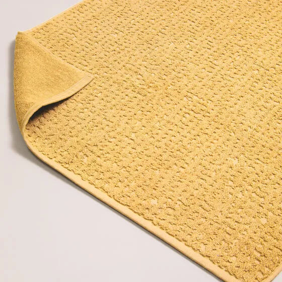 Luxe oker Florence badmat van 100% GOTS-katoen, 600 g/m², hoge kwaliteit, zacht en absorberend.
